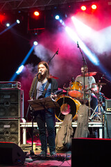 Rock group playing on the live concert outdoor in summer. Guitar player, singer, drummer and cellist.