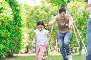 Fototapeta premium Young Asian parents doing activities eating and playing with their daughter in the front yard during the holidays happily.
