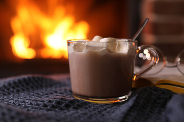 Delicious sweet cocoa with marshmallows and blurred fireplace on background