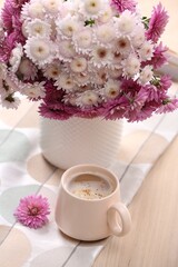 Cup of hot coffee and beautiful bouquet on wooden table