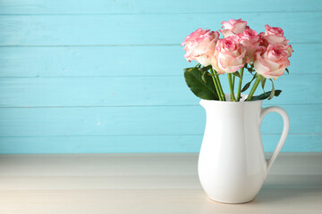 Vase with beautiful pink roses on wooden table. Space for text