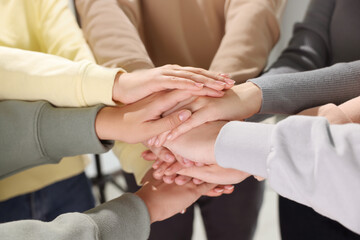 Group of people holding hands together indoors, closeup. Unity concept