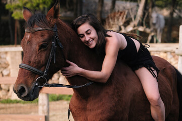 Amazon girl in black dress hugging her horse.