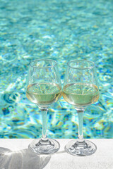 Glasses of tasty wine on swimming pool edge
