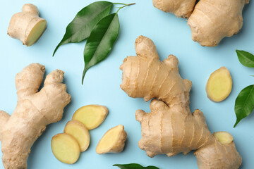 Fresh ginger with green leaves on pale light blue background, flat lay