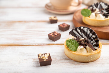 Sweet tartlets with chocolate and cheese cream with cup of coffee on a white wooden background. side view, selective focus.
