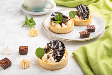 Sweet tartlets with chocolate and cheese cream with cup of coffee on a gray concrete background. side view.