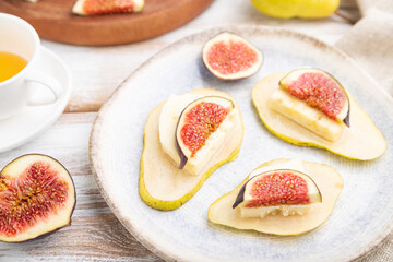 Summer appetizer with pear, cottage cheese, figs and honey on a white wooden background. Side view, selective focus.