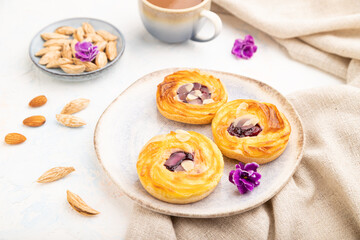 Small cheesecakes with jam and almonds with cup of coffee on a white concrete background. Side view, selective focus.