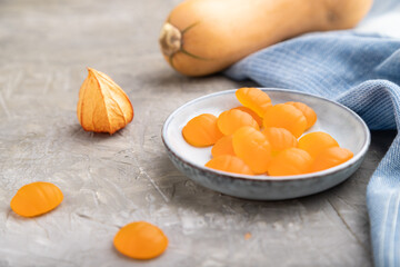 Jelly pumpkin candies on gray concrete background. close up, side view, selective focus.