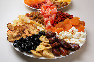 Plates with different dried fruits on white background