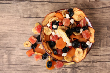 Bowl and different tasty dried fruits on wooden table, flat lay