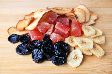 Pile of different tasty dried fruits on wooden table, closeup