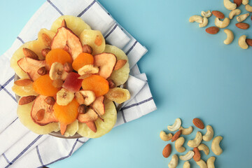 Mixed dried fruits and nuts on light blue background, flat lay