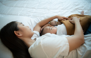A mother must sleep and rest with her newborn baby. In the white bedroom, warm sunlight in the evening of the day.