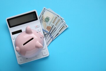 Piggy bank, calculator and banknotes on light blue background, flat lay. Space for text