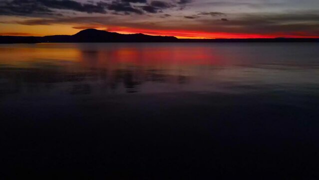 Dusk Dawn over hills shot from the edge of a large lake - drone slide to tree branches - Ocean and sea stock videos.