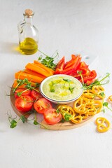 Vegetable tray with green peas and cream cheese dip on a light concrete background. Vegetarian recipes.