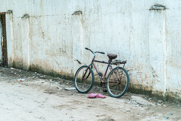 Fototapeta na wymiar Old rusty bike and shoes leaning on a dirty wall
