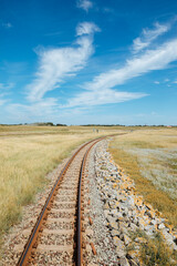 Railroad tracks running through a beautiful field. Rails through beautiful countryside with lots of greenery and blue skies. Train journey to Germany through beautiful landscapes