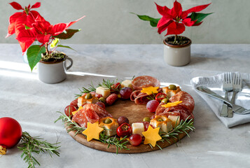 Christmas appetizers wreath on wooden board and grey background, star of Christmas plant or Poinsettia, napkin, forks - Powered by Adobe