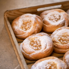 Rolls with the fruit filling, sprinkled with castor sugar in a wooden box. Serve of baking.