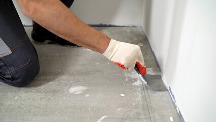 Close-up spatula cleans the floor. Close-up of a worker scraping debris from a concrete floor. The...