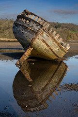Abandoned wreck of a vintage wooden fishing boat with reflections