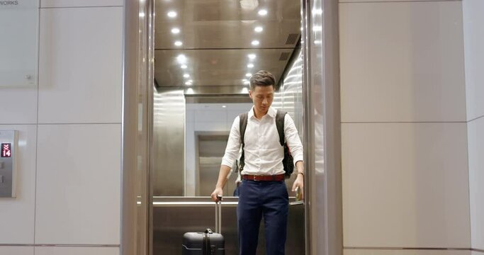 Travel, hotel elevator and man with suitcase on business trip in lobby in Japan. Hospitality, corporate traveler and businessman with luggage pressing button for floor with building lift door closing