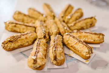 Eclairs sprinkled with almond flakes. Eclairs with cream. Close up. Candy bar.