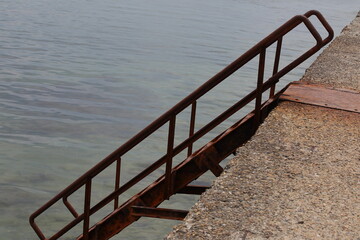 Stairs to the sea from the pier with rusty steps