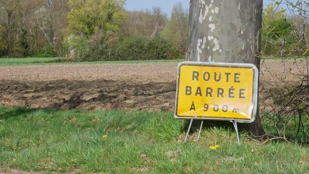 Tilt up showing a "Close Road" sign in french on a rural area