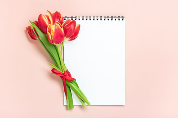 Bouquet of red tulips, gift box heart, notepad on pink background Top view Flat lay Holiday greeting card Happy moter's day, 8 March, Valentine's day, Easter concept Copy space Mock up