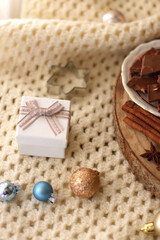 Various Christmas decorations, cup of tea or coffee, sweets, small presents, knitted blanket and candles. Selective focus.
