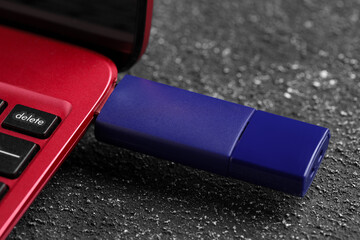 Usb flash drive attached into laptop on grey textured table, closeup