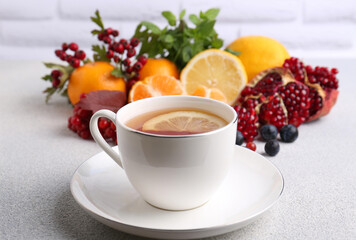 Cup of delicious immunity boosting tea with ingredients on light grey table