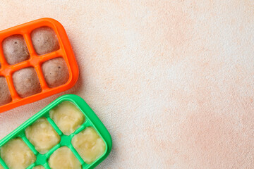 Apple and banana puree in ice cube trays on beige table, flat lay. Space for text