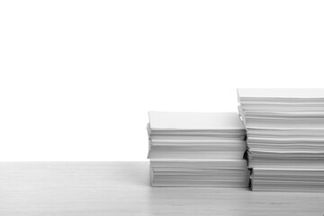 Stacks of paper sheets on light wooden table against white background. Space for text