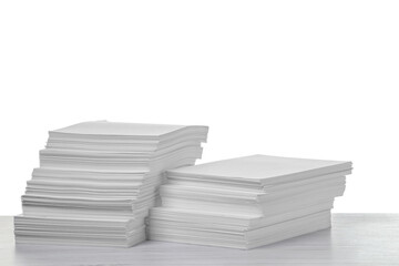 Stacks of paper sheets on light wooden table against white background