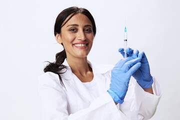 Woman doctor with syringe in hand in medical gown on white background nurse in blue gloves,...