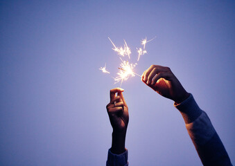 Sparkler, hand and person at night for new years eve celebration with bright, burning fun to celebrate. Celebrating, sparkle and blue nighttime background with a firework or firecracker in hands - obrazy, fototapety, plakaty