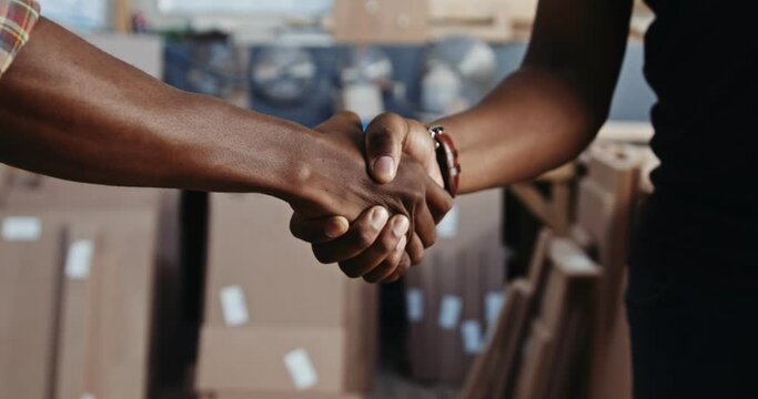 Male African carpentry factory workers shaking hands close up