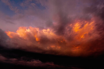 colorful dramatic sky with clouds, smoking cumulonimbus clouds reflect the golden light of the dawn sun.	