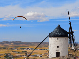 Windmills in the town of Consuegra de Toledo on a summer afternoon, with paragliders flying.