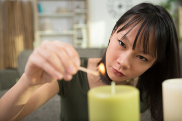 woman lighting up the candle on the candle - obrazy, fototapety, plakaty