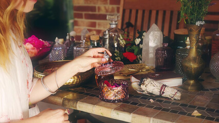 Rose flower for the preparation of essential oil. Spa and aromatherapy. Woman smells of rose petals. Background with sage incense, ceremony space.