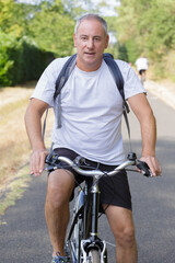 Obraz premium mature man riding bike in the mountain