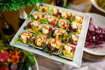 Close-up of shrimp appetizers with pineapple and cherry tomatoes on a white plate