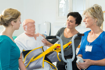 trainee nurses using mannequin in medical hoist