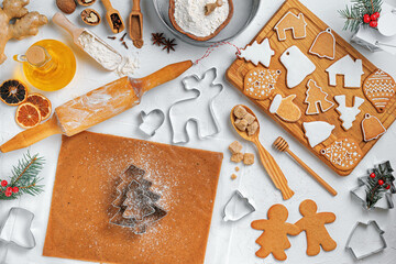 Christmas gingerbread different shaped with sugar icing and ingredients for gingerbread on wooden table, top view, flat lay